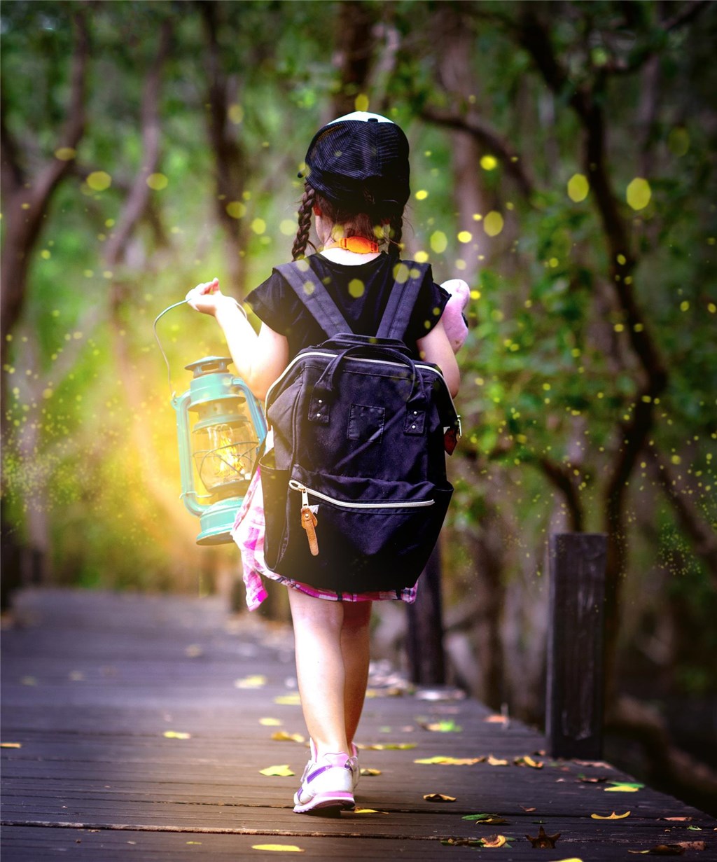 Child with backpack and lantern walking through forest and fireflies