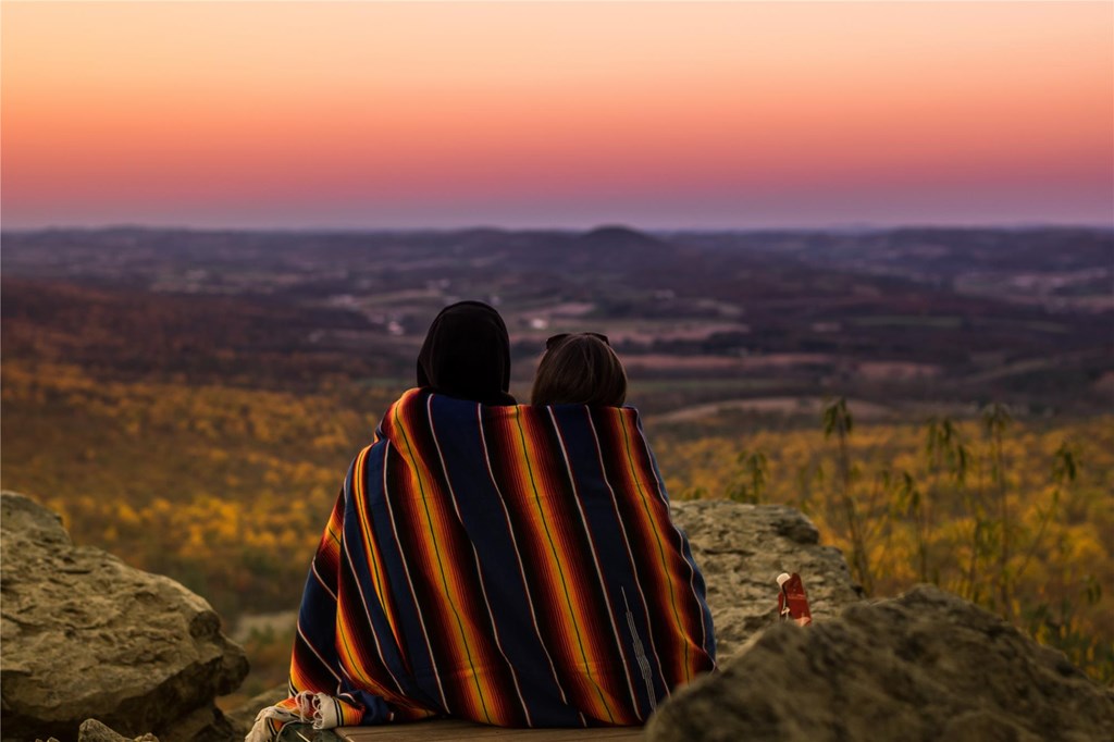A couple wrapped in a blanket enjoy the sunset over the vista from South Lookout