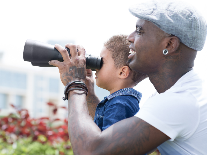 Father and son use binoculars