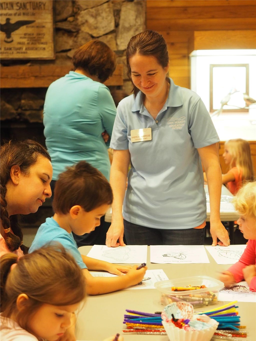 Educator Andrea oversees children completing a craft about butterflies