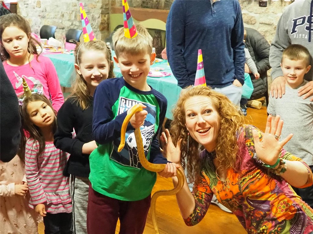 Educator and birthday party attendees interact with an education snake