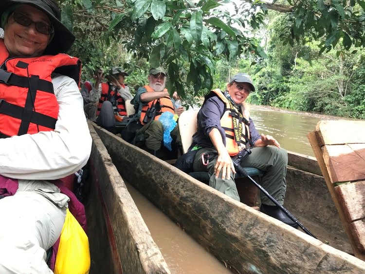People are smiling at camera on river in dugout canoes People in Dugout Canoes