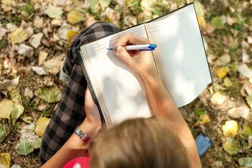 Woman writing in her journal outside Woman writing in her journal outside